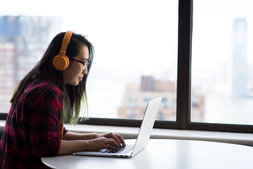 Asian woman with headphones using laptop for remote work in a city setting working on affiliate links for her blog