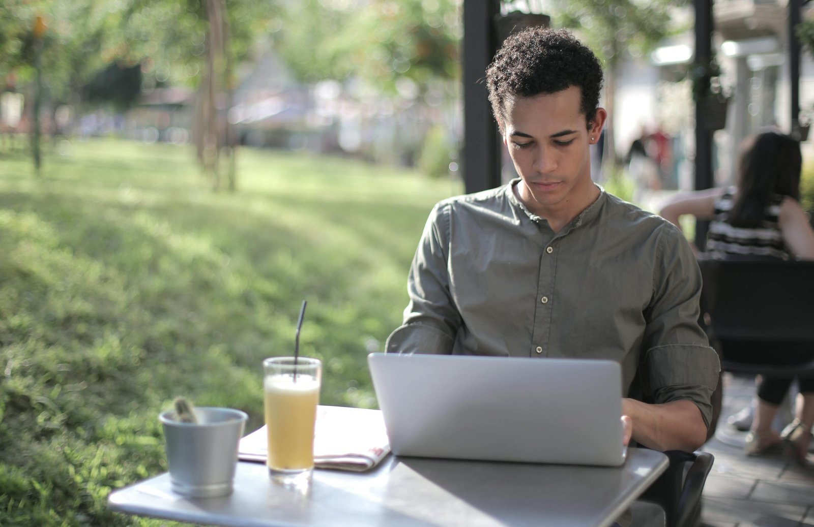 Young man working on a laptop outside in a casual and relaxed setting, enjoying a drink thinking about the purpose of blogging.