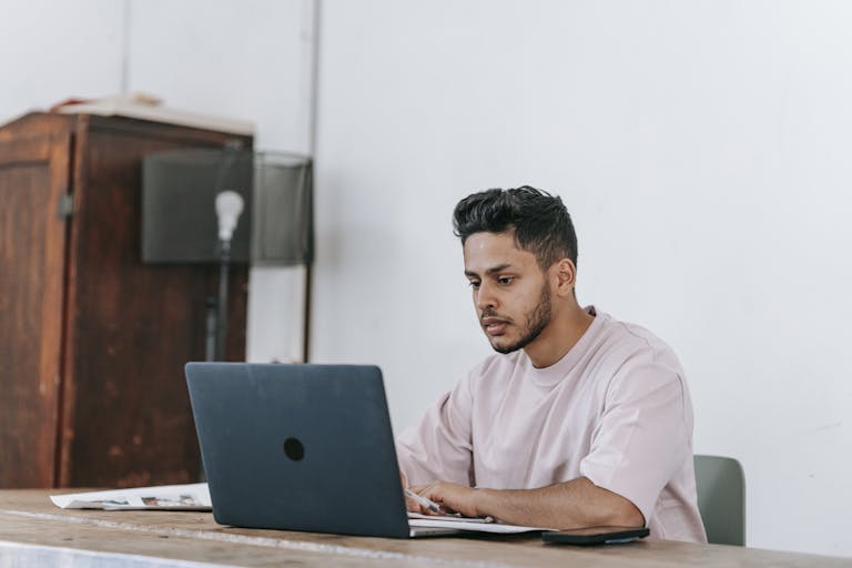 Focused young man working on a laptop learning how to create a website to sell digital products