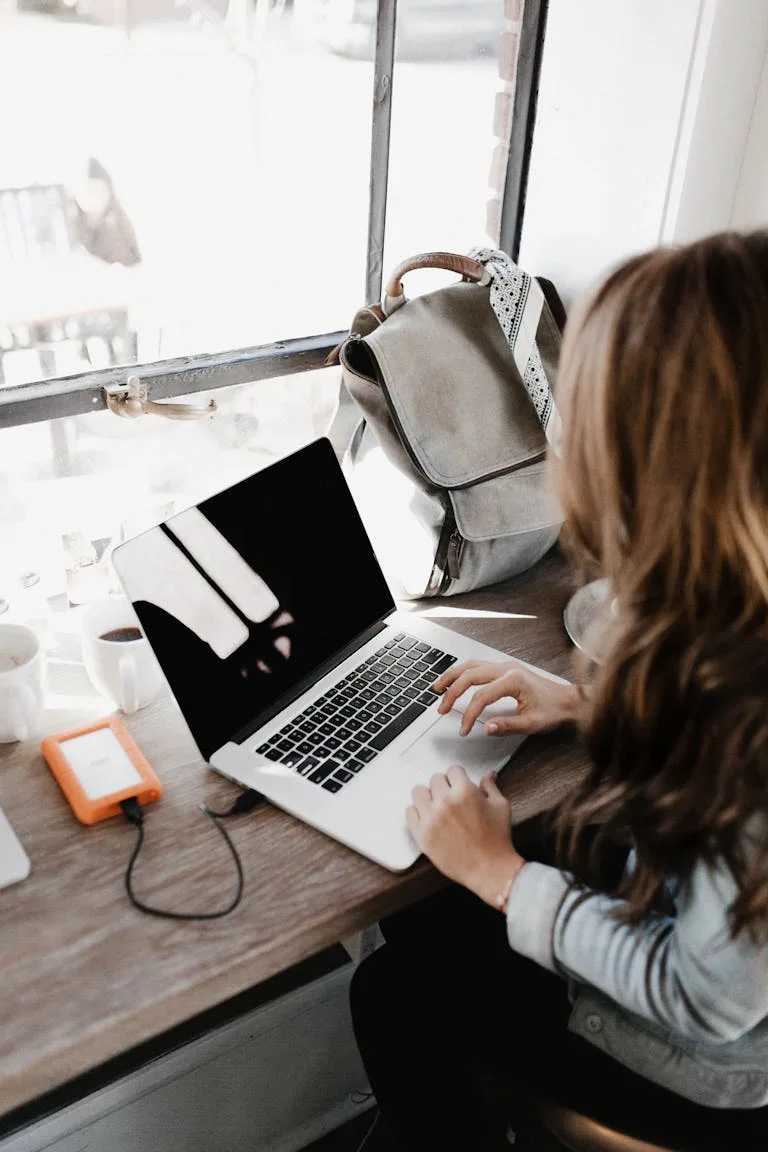 A young woman works remotely at a café, using her laptop to work on how to build blog traffic