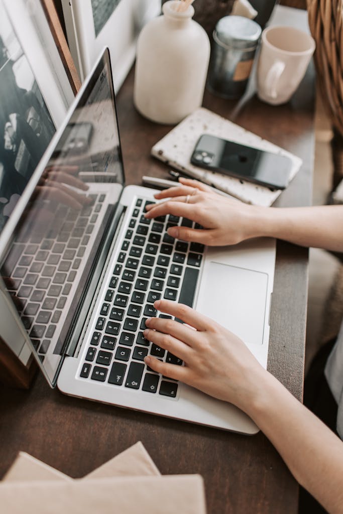From above of unrecognizable woman sitting at table and typing on keyboard of computer during remote work in modern workspace testing ubersuggest vs ahrefs