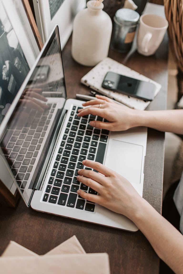 From above of unrecognizable woman sitting at table and typing on keyboard of computer during remote work in modern workspace testing ubersuggest vs ahrefs