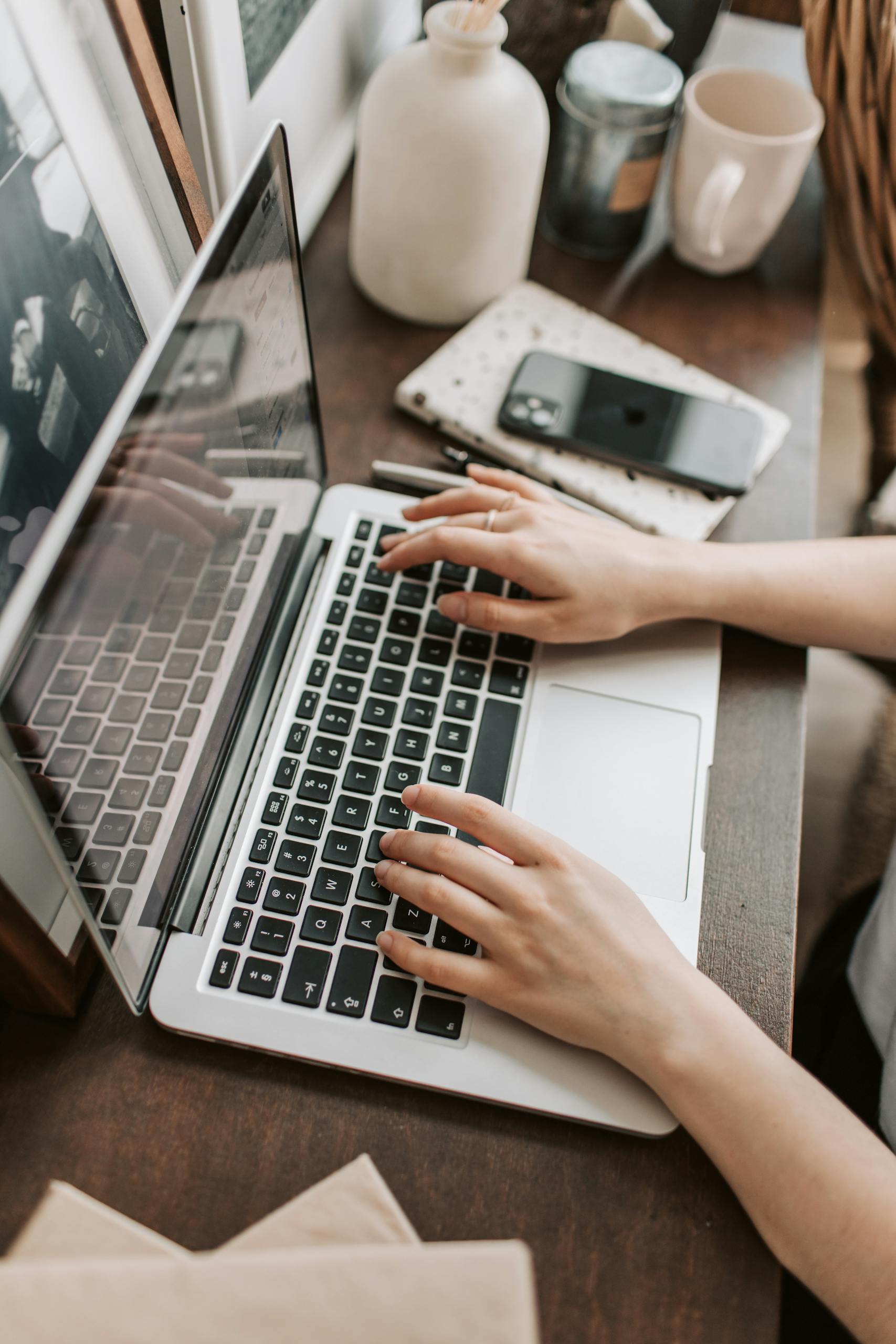 From above of unrecognizable woman sitting at table and typing on keyboard of computer during remote work in modern workspace testing ubersuggest vs ahrefs