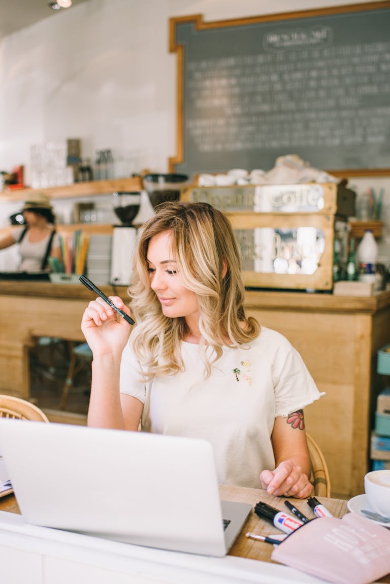 Woman working on laptop in a bright café, embodying remote work and working on passive income blog