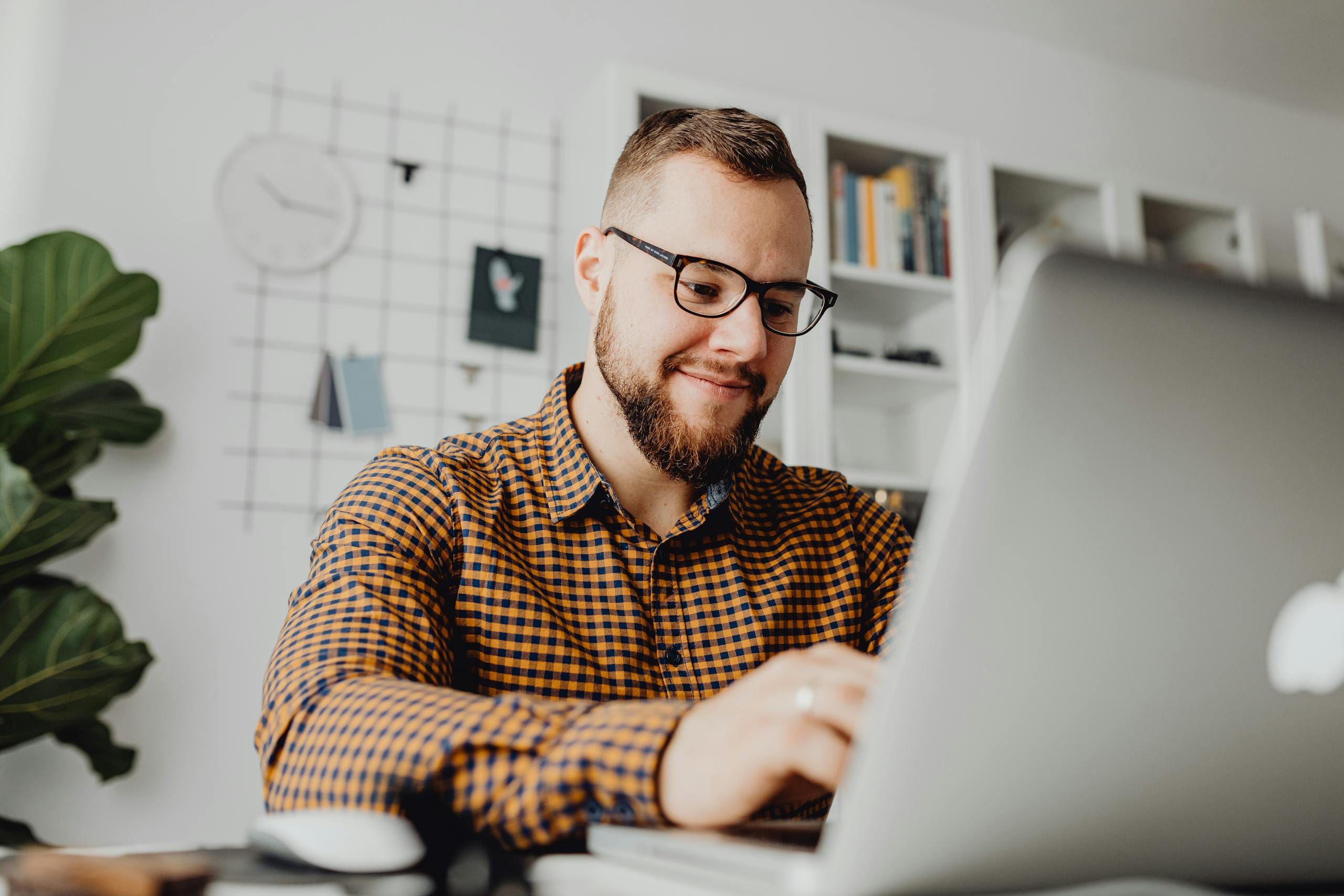 A confident man with glasses working on a laptop and AI SEO in a modern office setting.