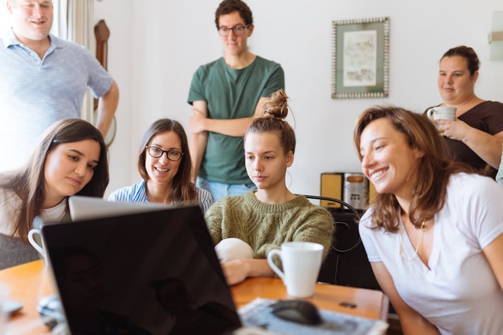 A diverse group of adults at work, enjoying a casual meeting indoors with focus and smiles working on best AI prompts